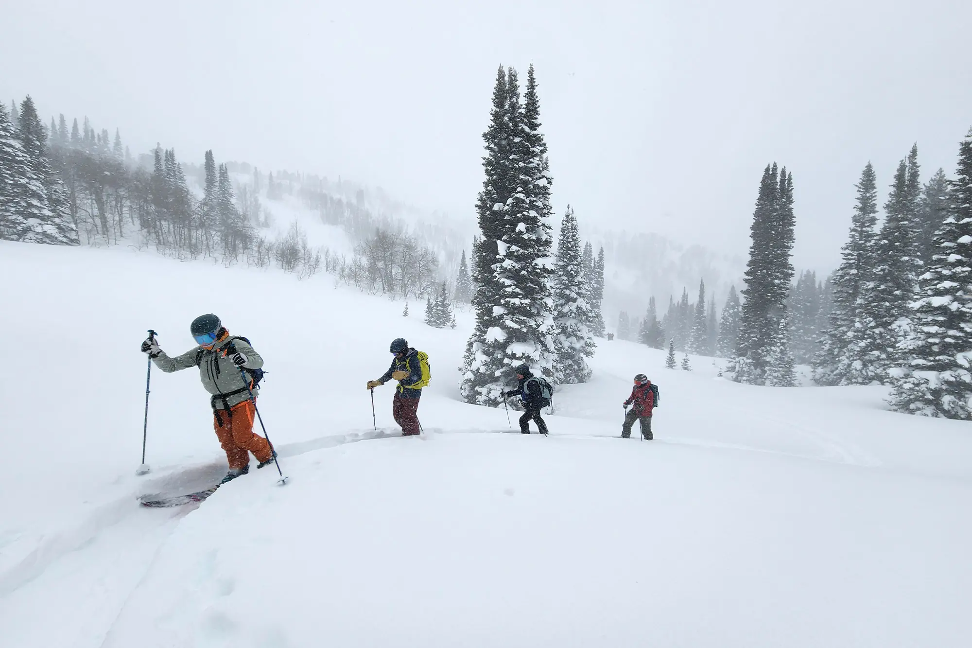 A group of skiers ascending a snowy mountain ridge in deep powder conditions
