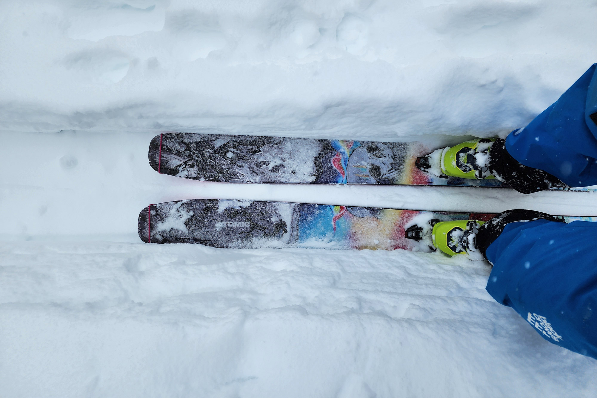 A top-down view of a skier's boots and skis in fresh snow