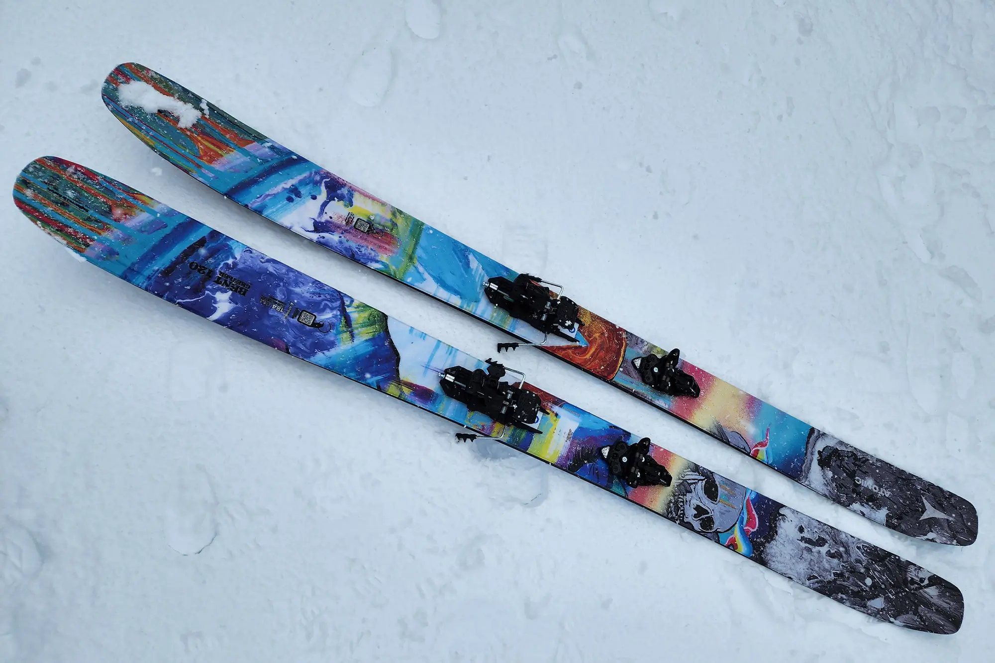 A close-up of colorful Atomic Bent Chetler 120 skis resting on snow