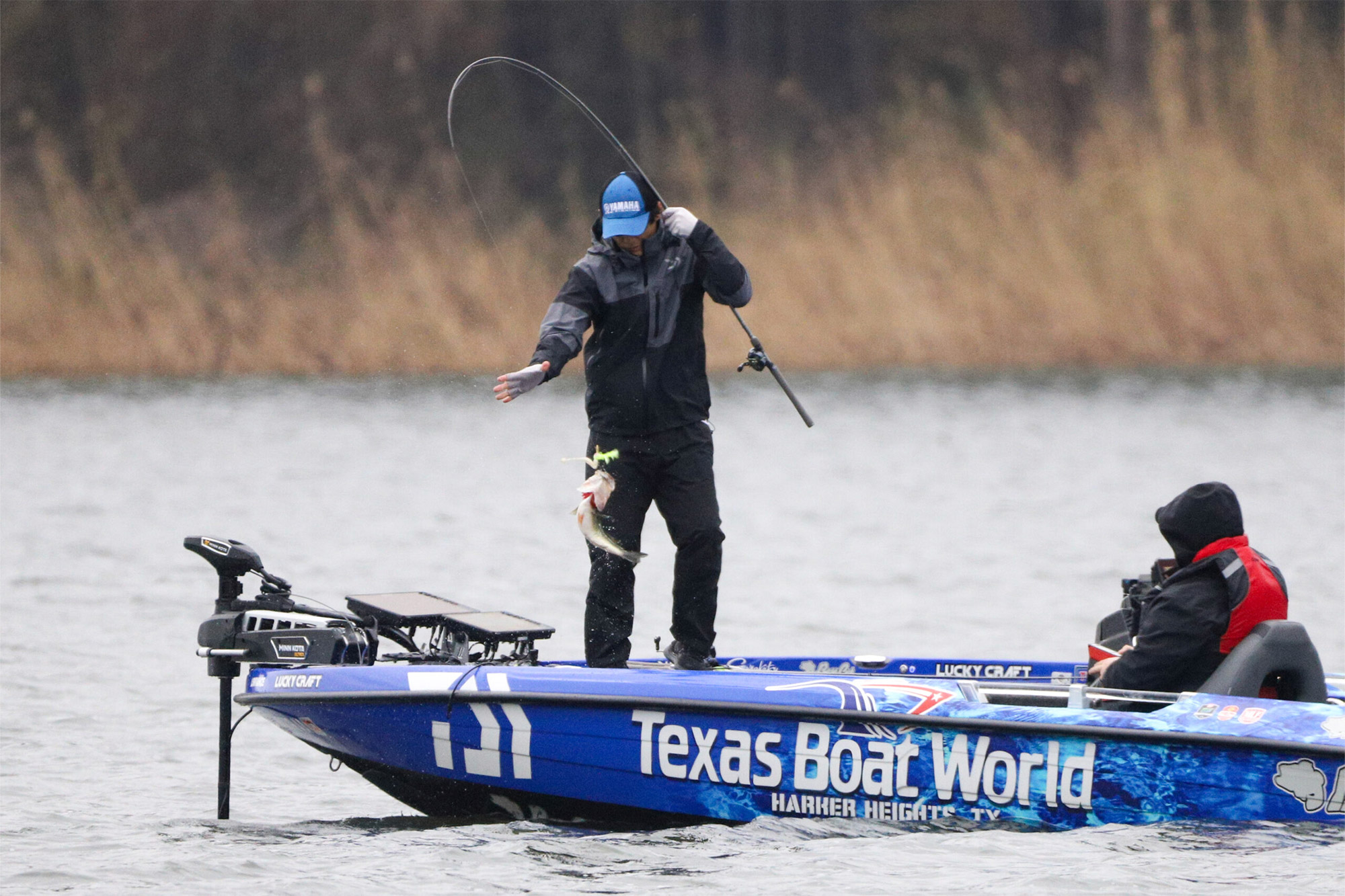 An angler skillfully pulls in a bass while standing on his boat
