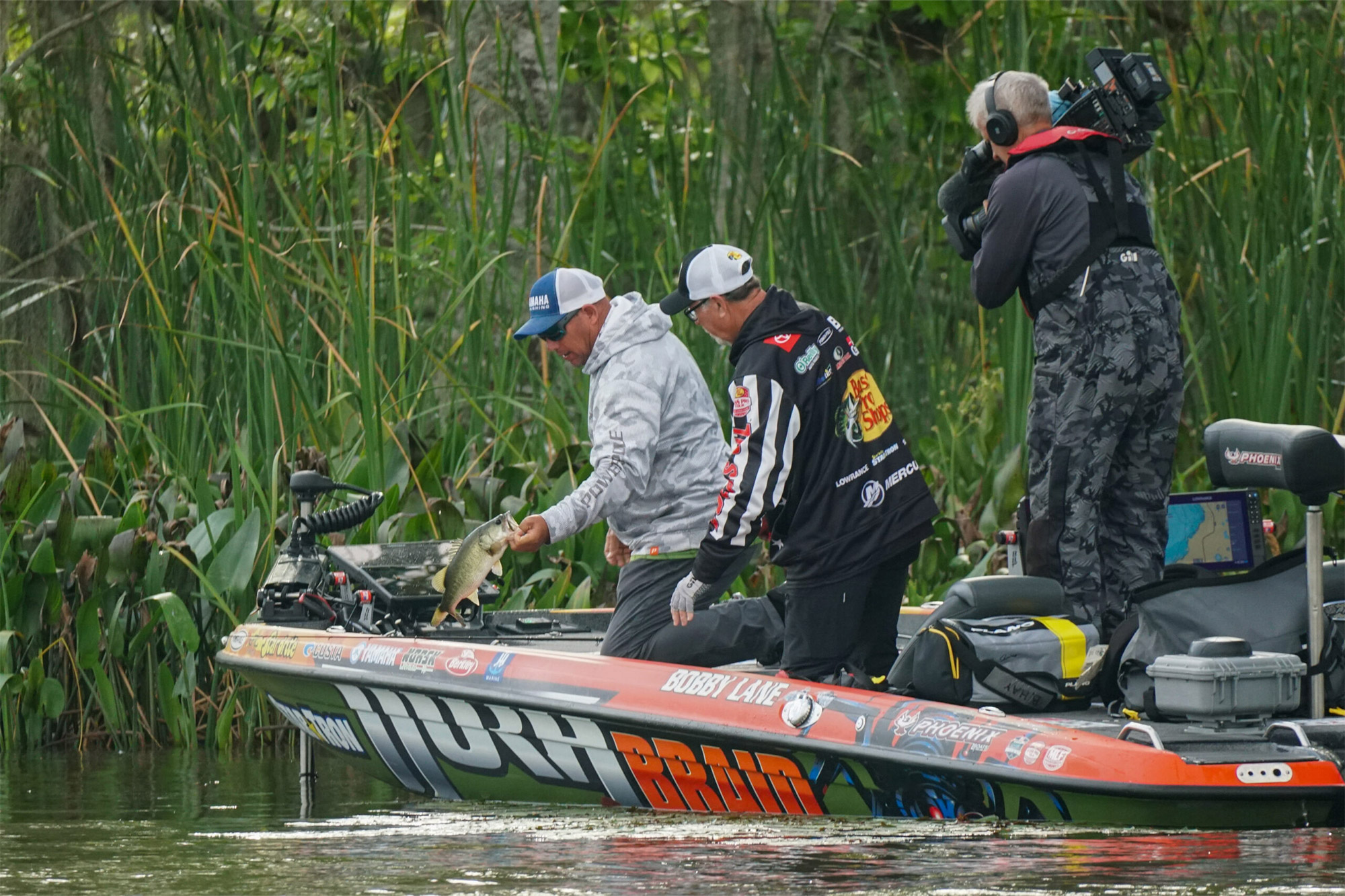 Bobby Lane holds up a largemouth bass on Championship Day as a cameraman captures the moment
