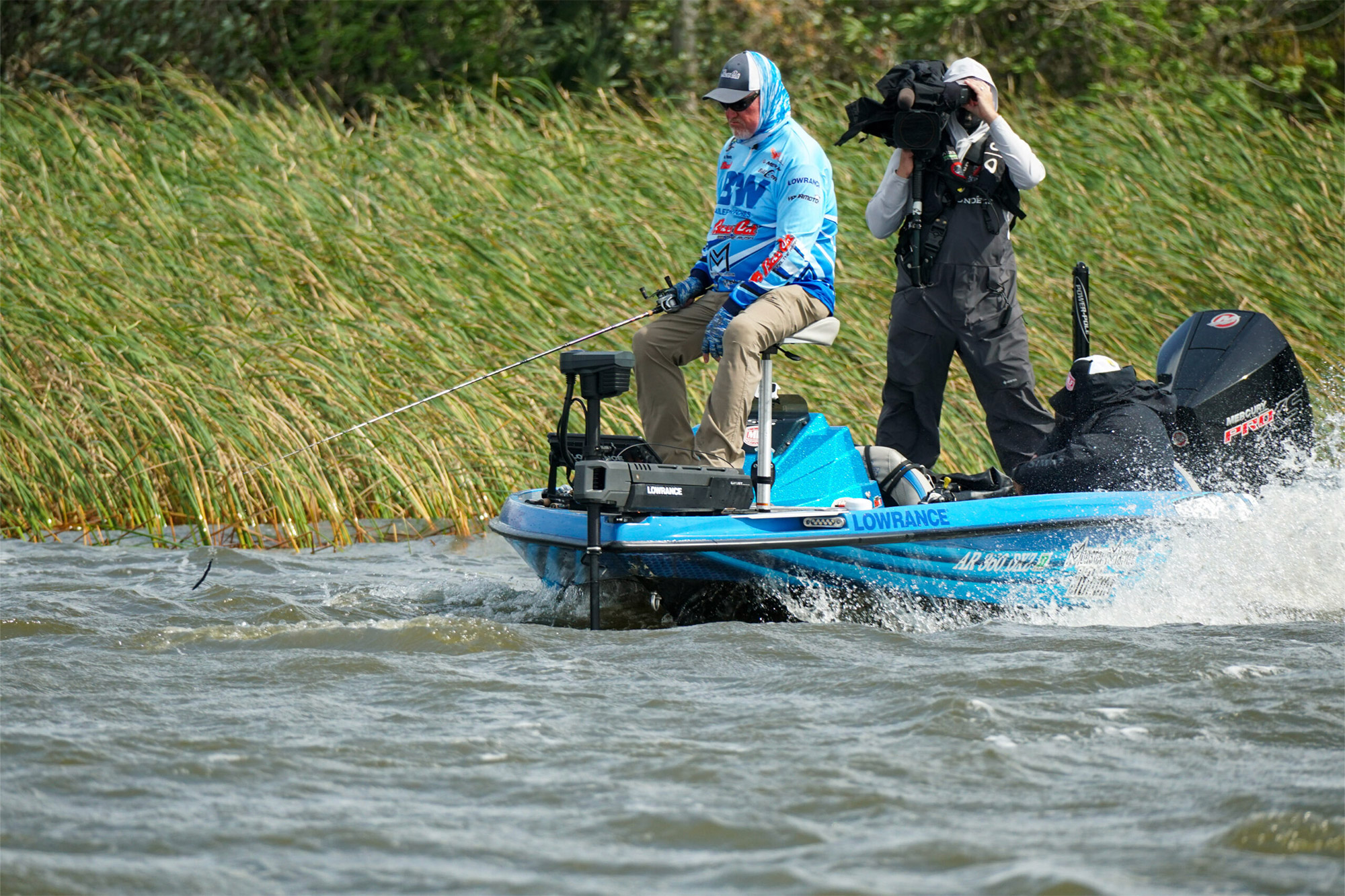 Mark Davis fishes in windy conditions as waves crash against his boat, with a cameraman capturing the moment