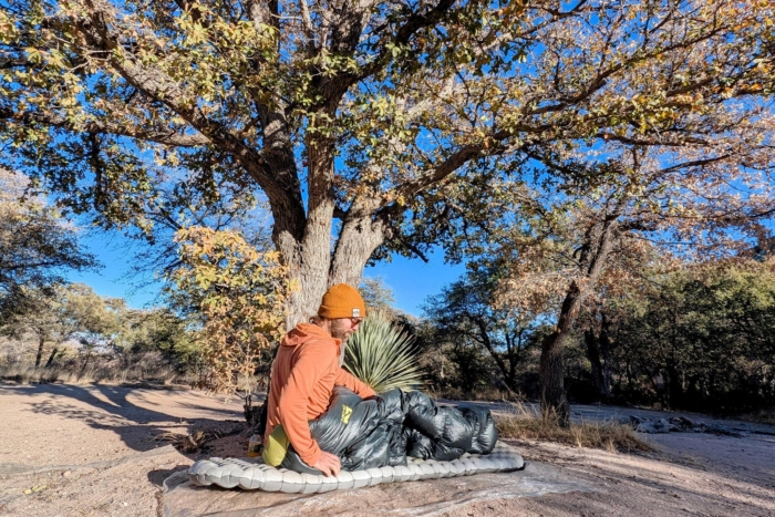 Camper sitting on the NEMO Tensor Elite Sleeping Pad in an outdoor setting