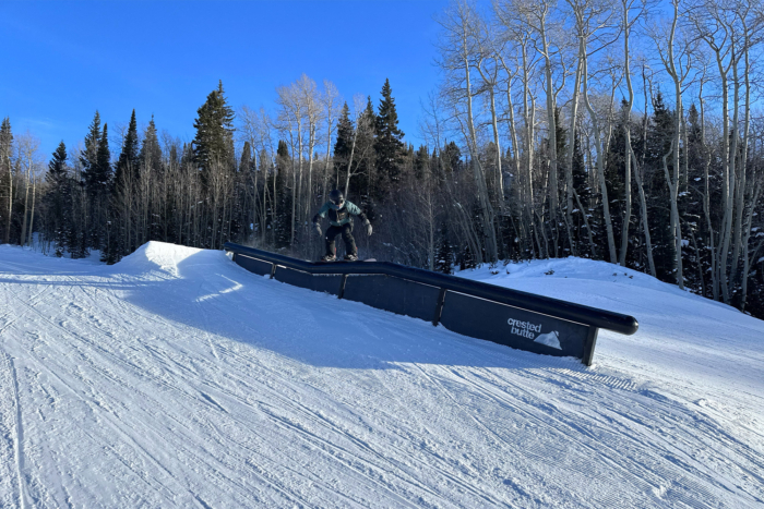 A snowboarder mid-grind on a rail feature at Crested Butte