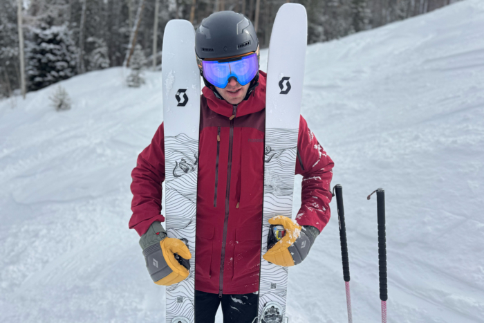 A skier holding the Scott SEA 108 skis upright, showing off the topsheet design