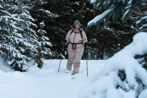 Person wearing the Trew Gear Women’s Stella Jacket PRIMO-Plus, skiing through a snowy forest