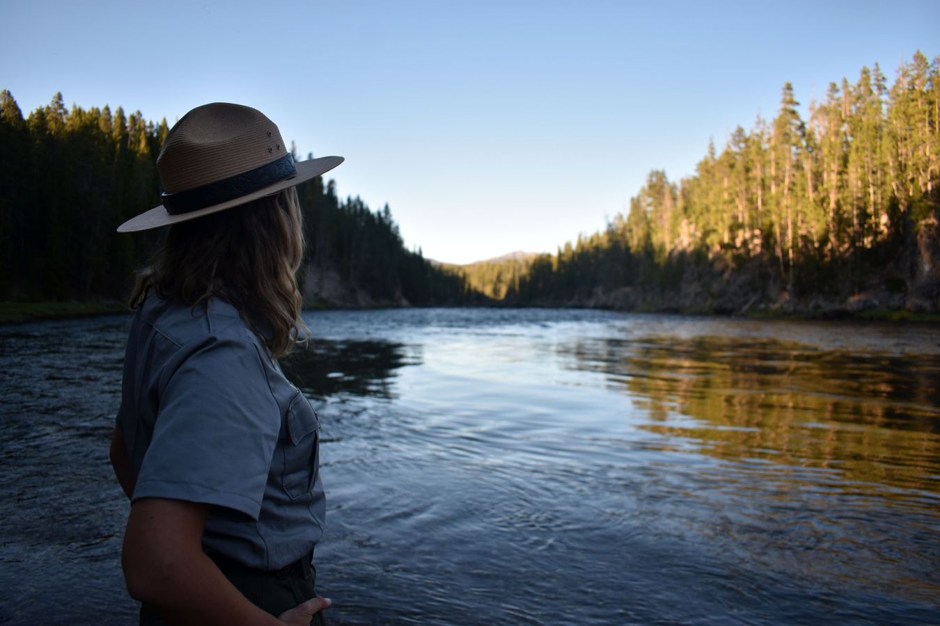 Silhouetted female park ranger stands next to the mighty Yellowstone River - Wyoming, USA