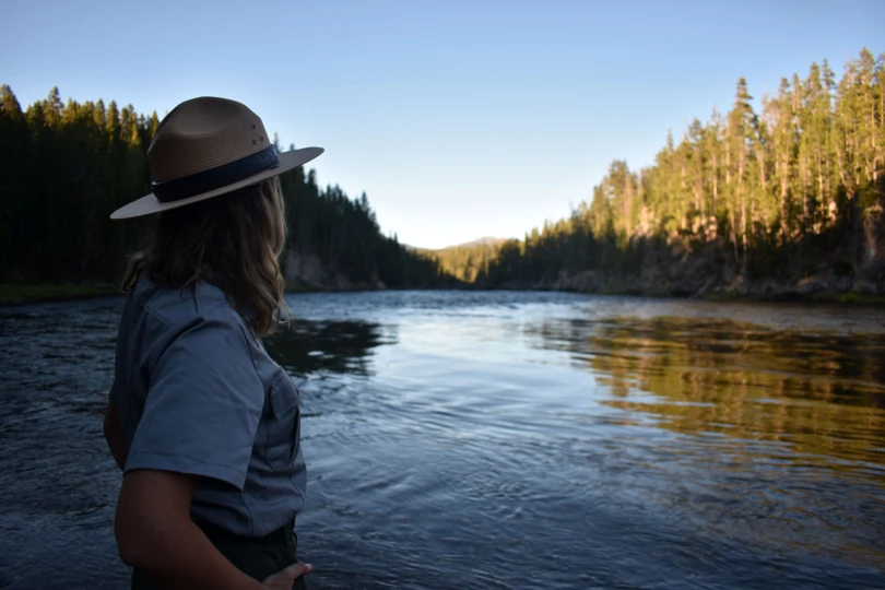 Silhouetted female park ranger stands next to the mighty Yellowstone River - Wyoming, USA