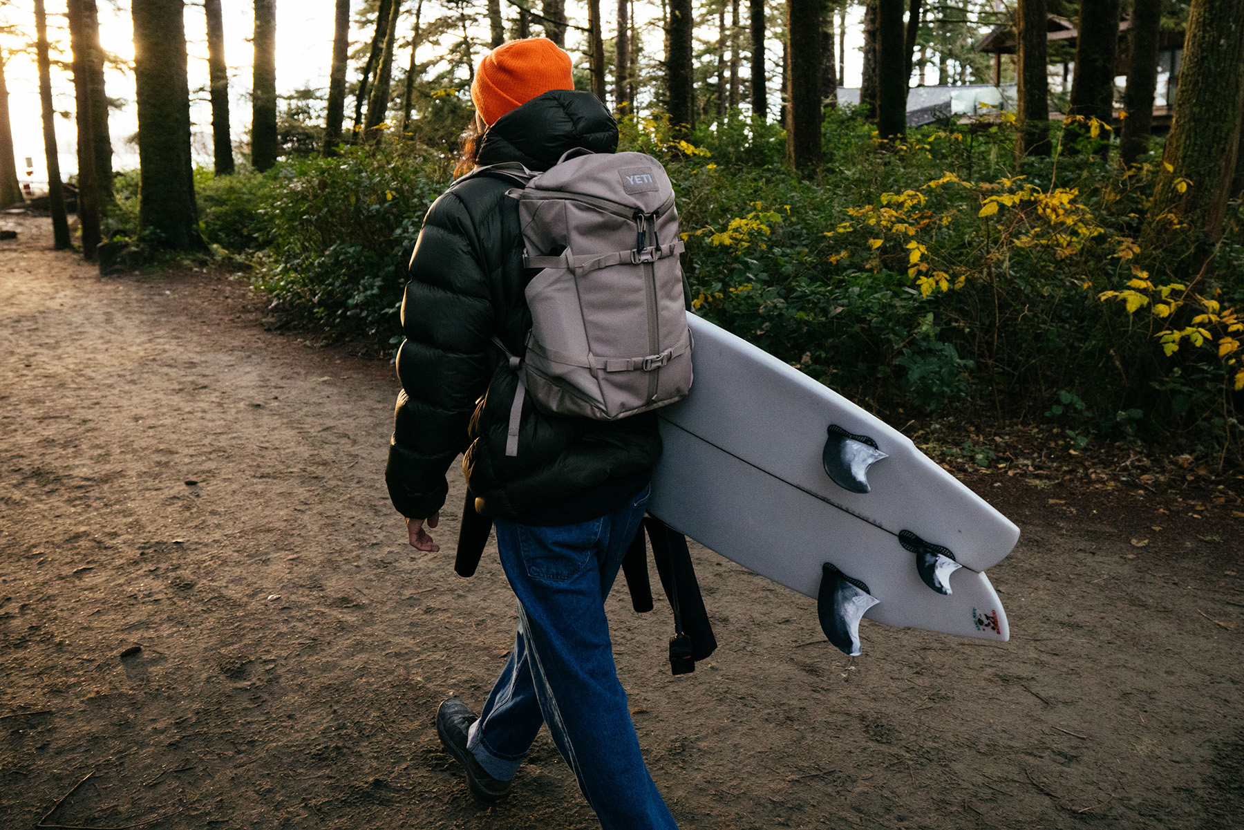 woman carrying surfboard with YETI backpack