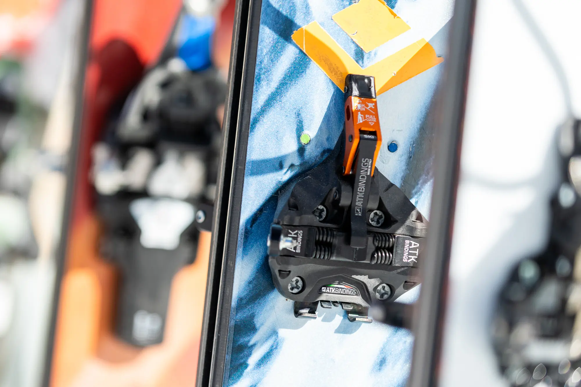 A close-up of an ATK Raider 13 Evo binding mounted on a ski, showing the toe piece and its release mechanism