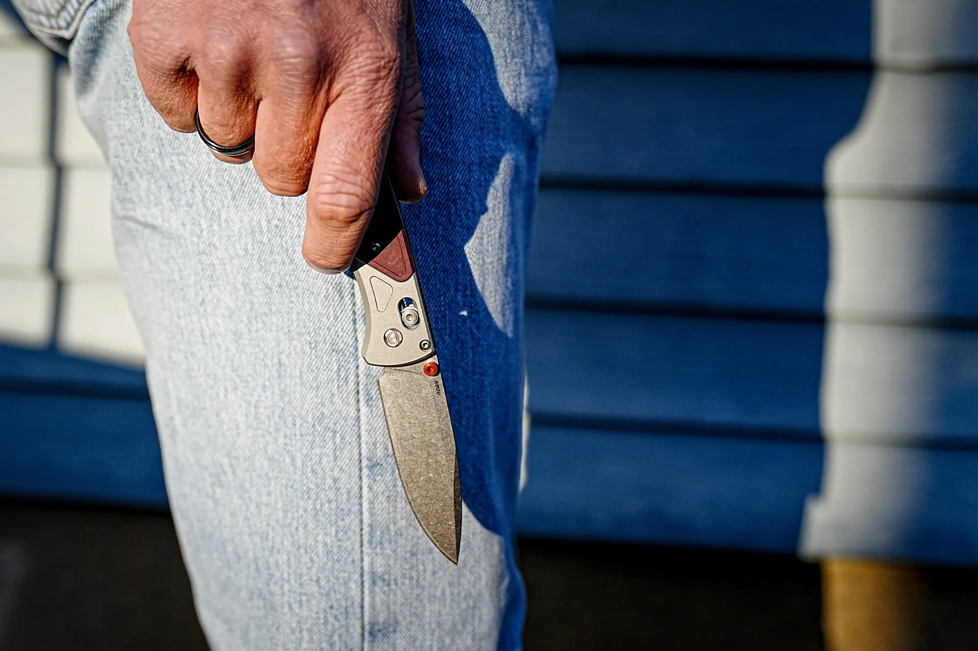 The Benchmade Bugout 535-09 is being held in hand outdoors with a blurred background