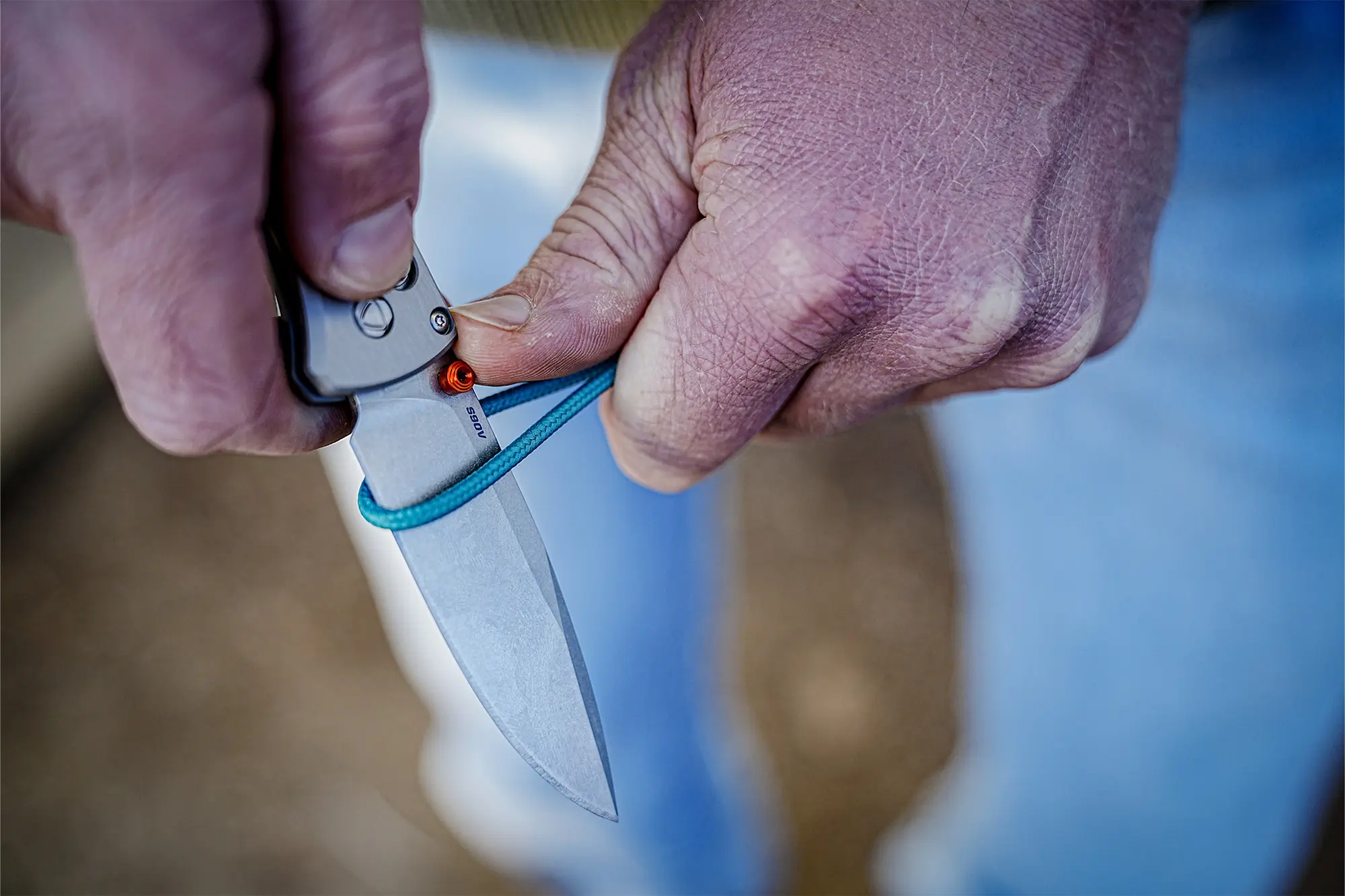 The Benchmade Bugout 535-09 is being used to cut a piece of paracord