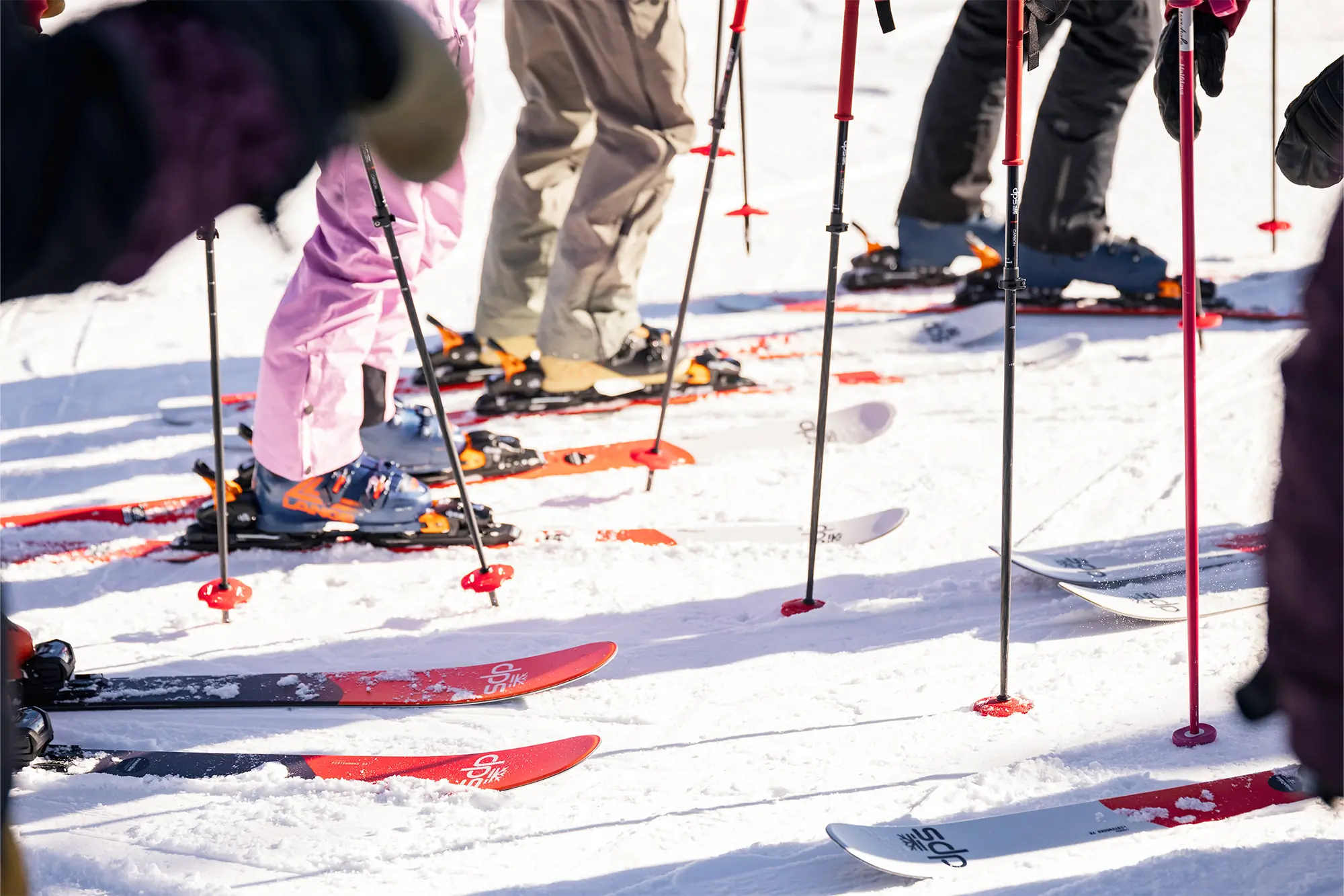 A group of skiers standing in the snow with DPS Pisteworks 79 skis lined up