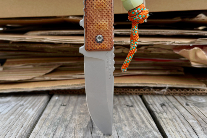 Dauntless Manufacturing Hiker with orange paracord, displayed against a cardboard background