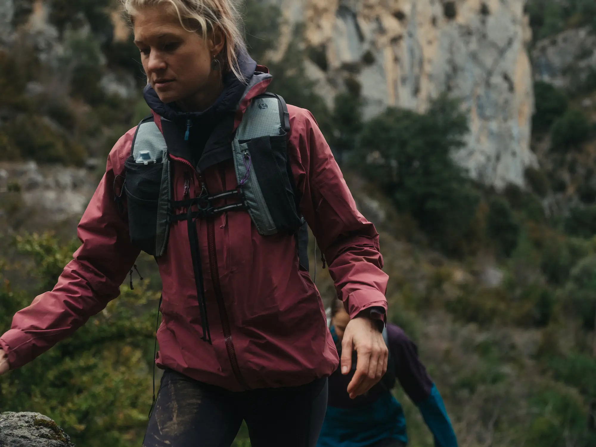 Woman wearing pink rain jacket and backpack hiking
