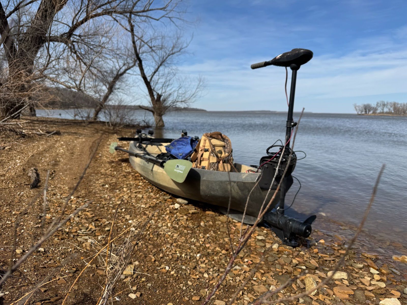 The kayak is positioned on the shore, ready for the hunt with its motor and gear