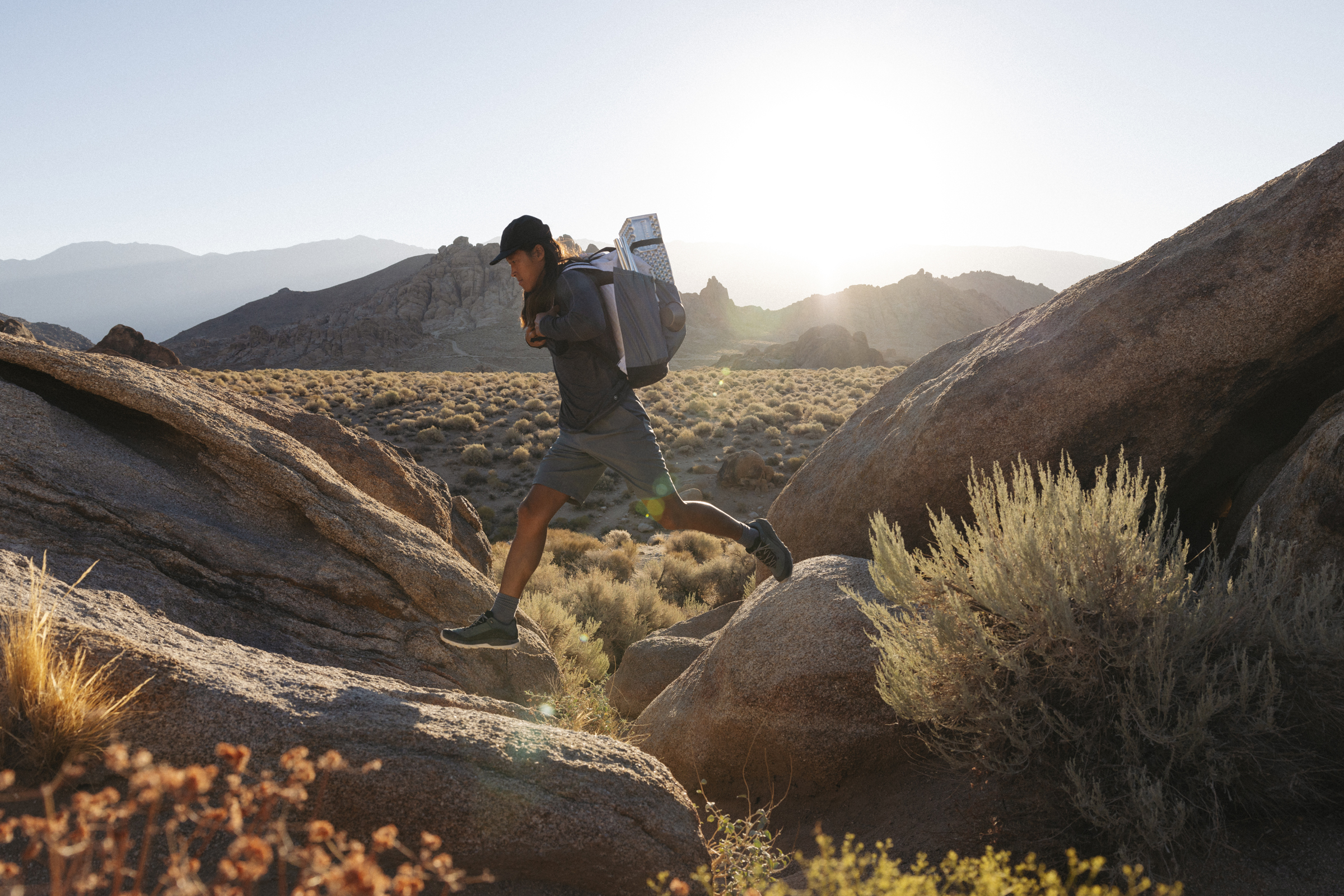 Person leaping from rock to rock in desert wearing backpack