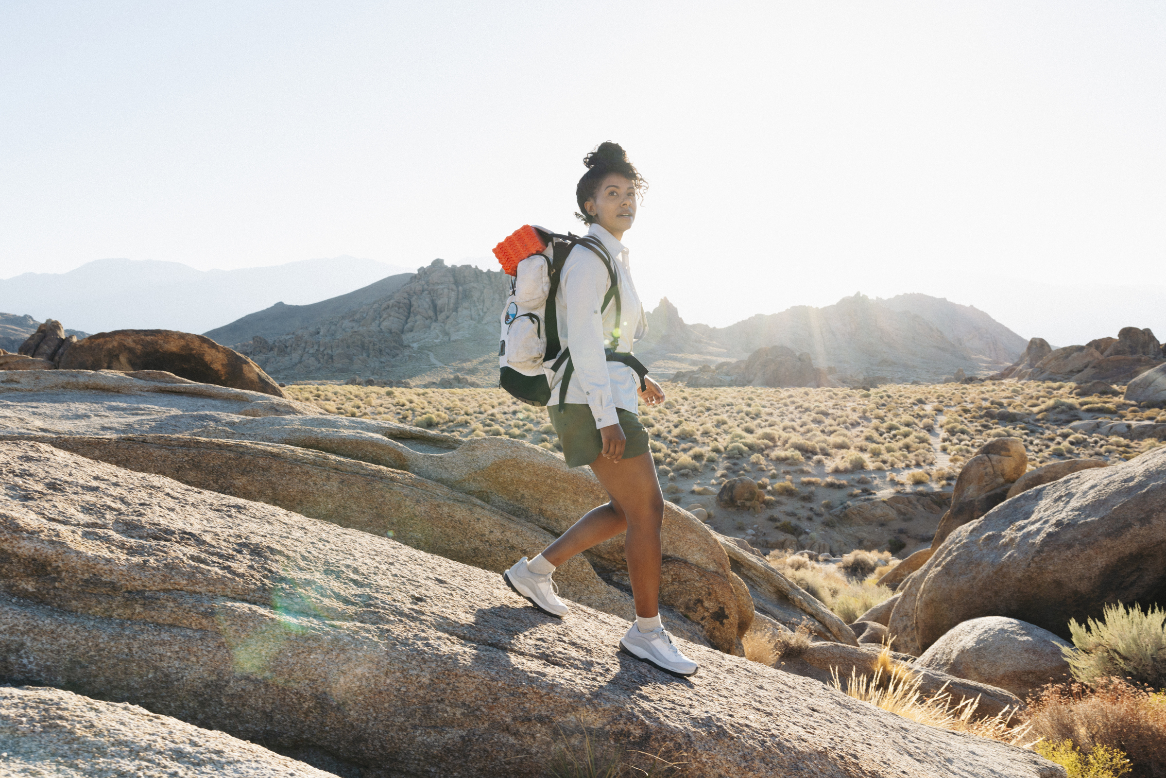 Woman walking down rock with mountains in background