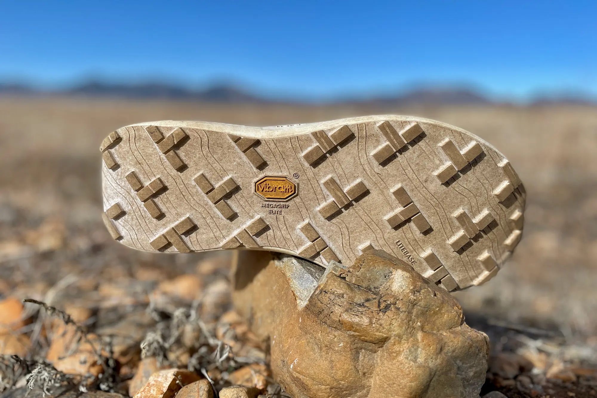 Norda 005 outsole resting on a rock, showing its Vibram Megagrip Litebase tread pattern
