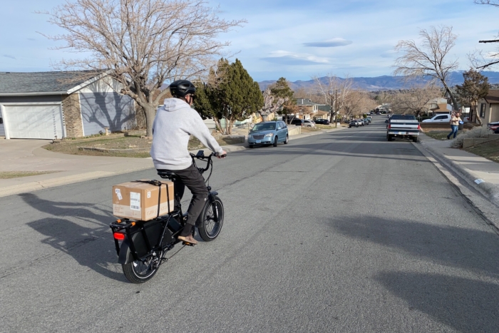 Riding the RadWagon 5 down a paved road in a neighborhood with a box strapped on the cargo rack