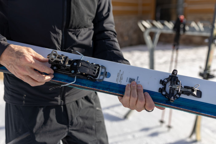 A skier adjusts the Salomon MTN Pure bindings on a ski
