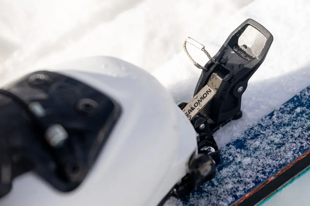 The Salomon MTN Pure toe piece with a ski boot and leash attachment point in the snow