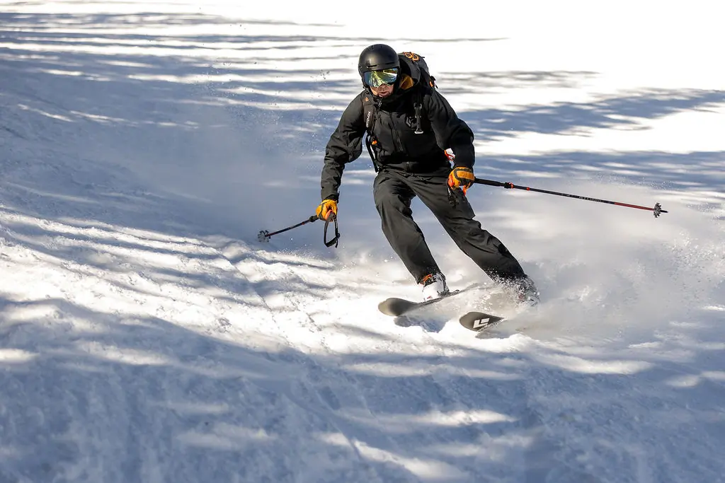  A skier makes a sharp turn on a snow-covered slope, kicking up powder in mid-action