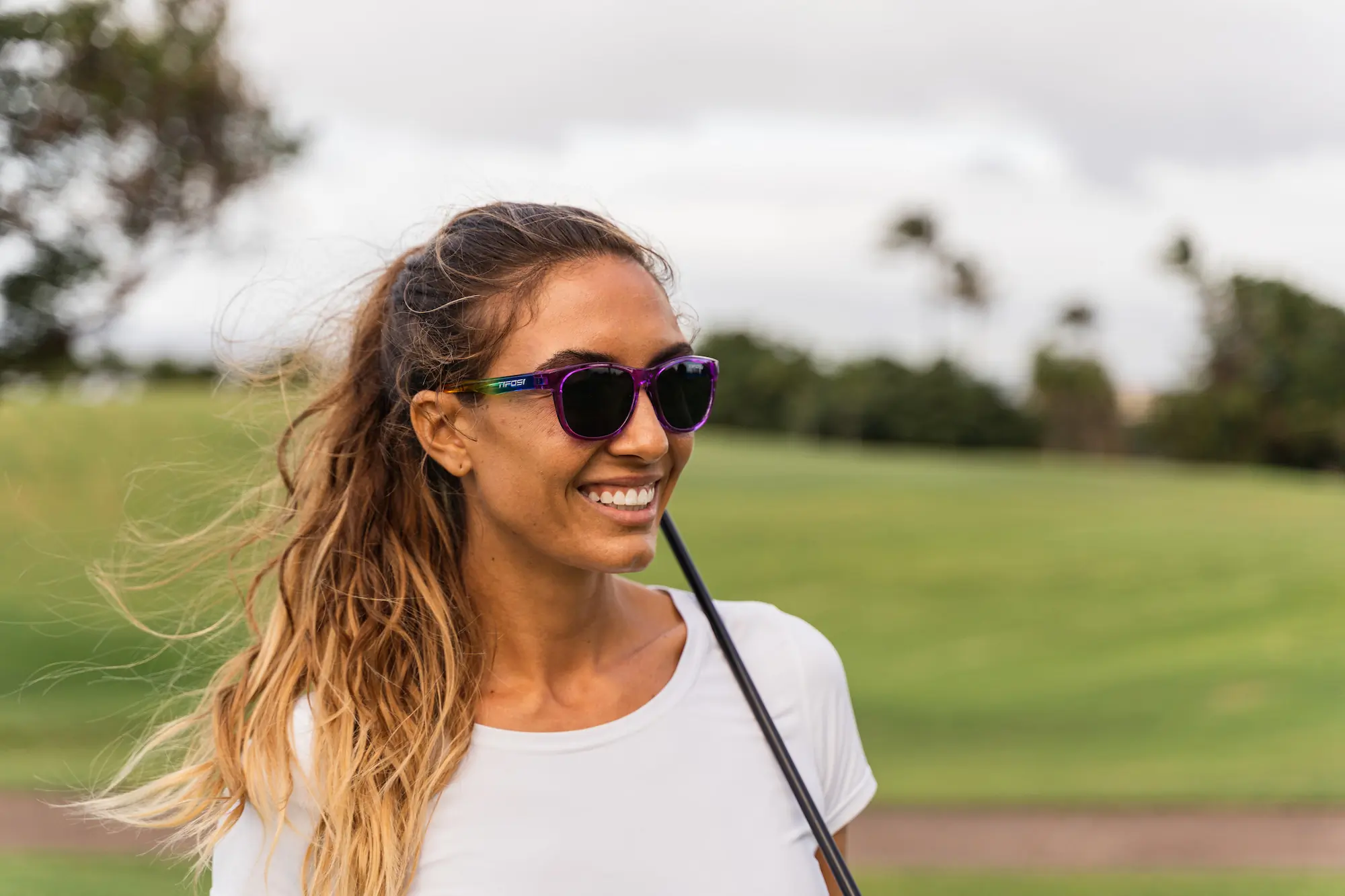 Woman with pony tail in sunglasses on golf course