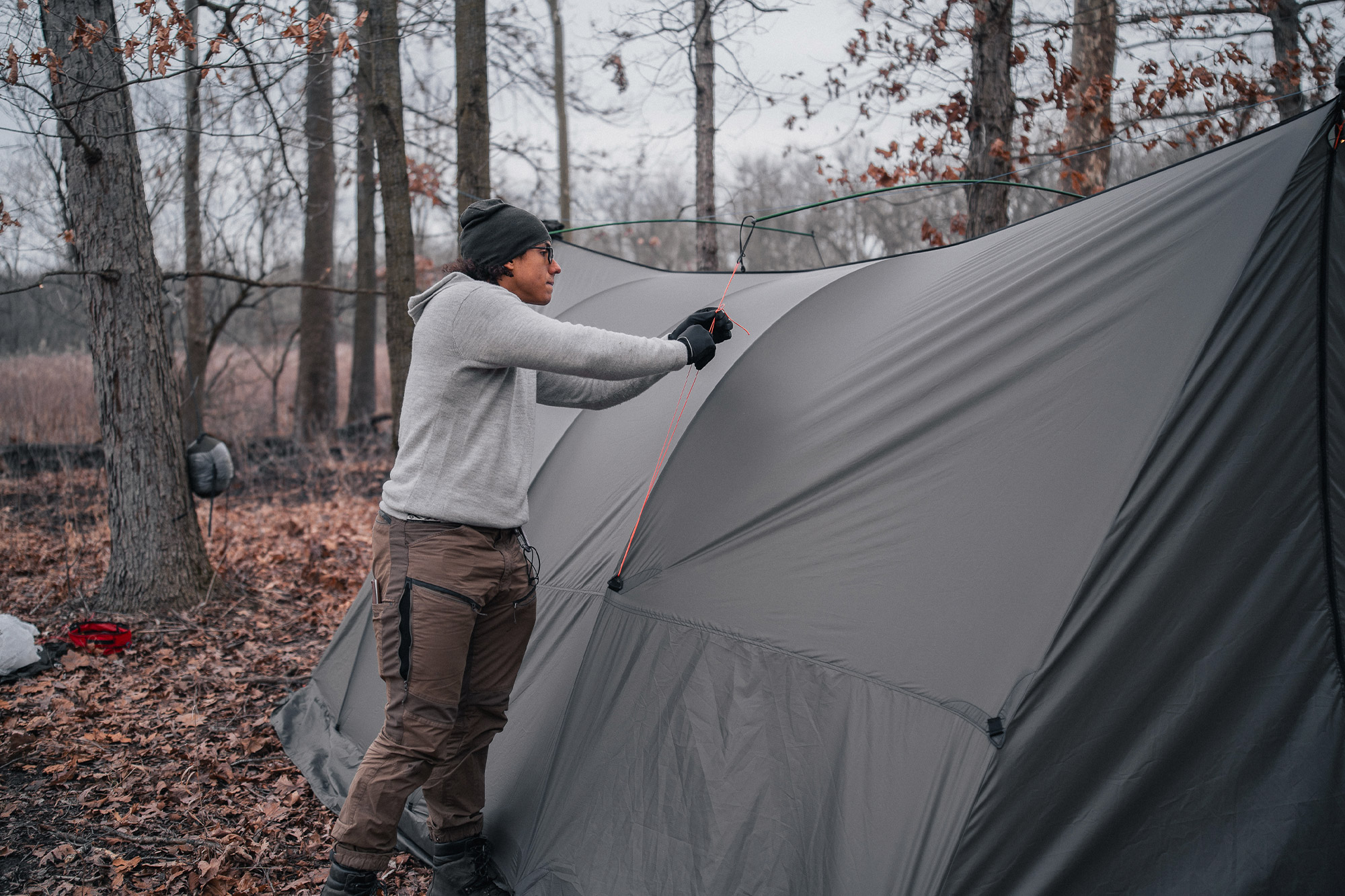 Camper tightens a guyline to elevate the Warbonnet Tsunami’s midsection