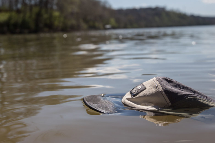 Turtle Fur Way Out 5 Panel Fishing Hat floating in a river.