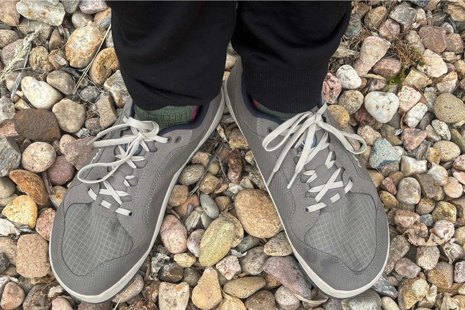 A pair of Astral NoSobo hiking shoes worn by a hiker standing on a rocky trail,