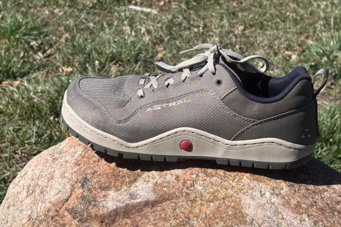 A side profile of the Astral Nosobo shoe resting on a rock, highlighting its rugged sole