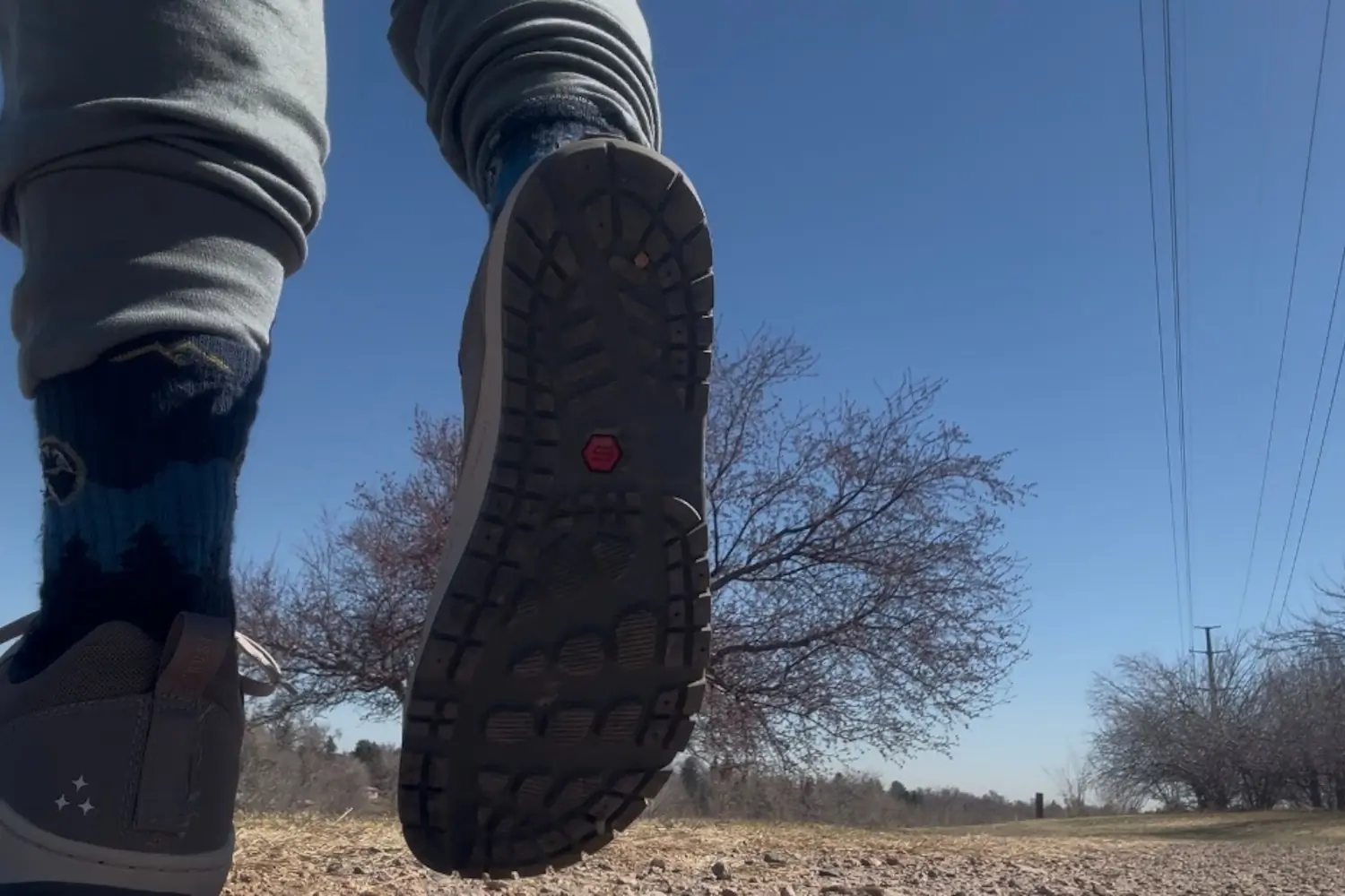 Low-angle shot of a person walking on a dirt trail, wearing Astral NoSobo shoes