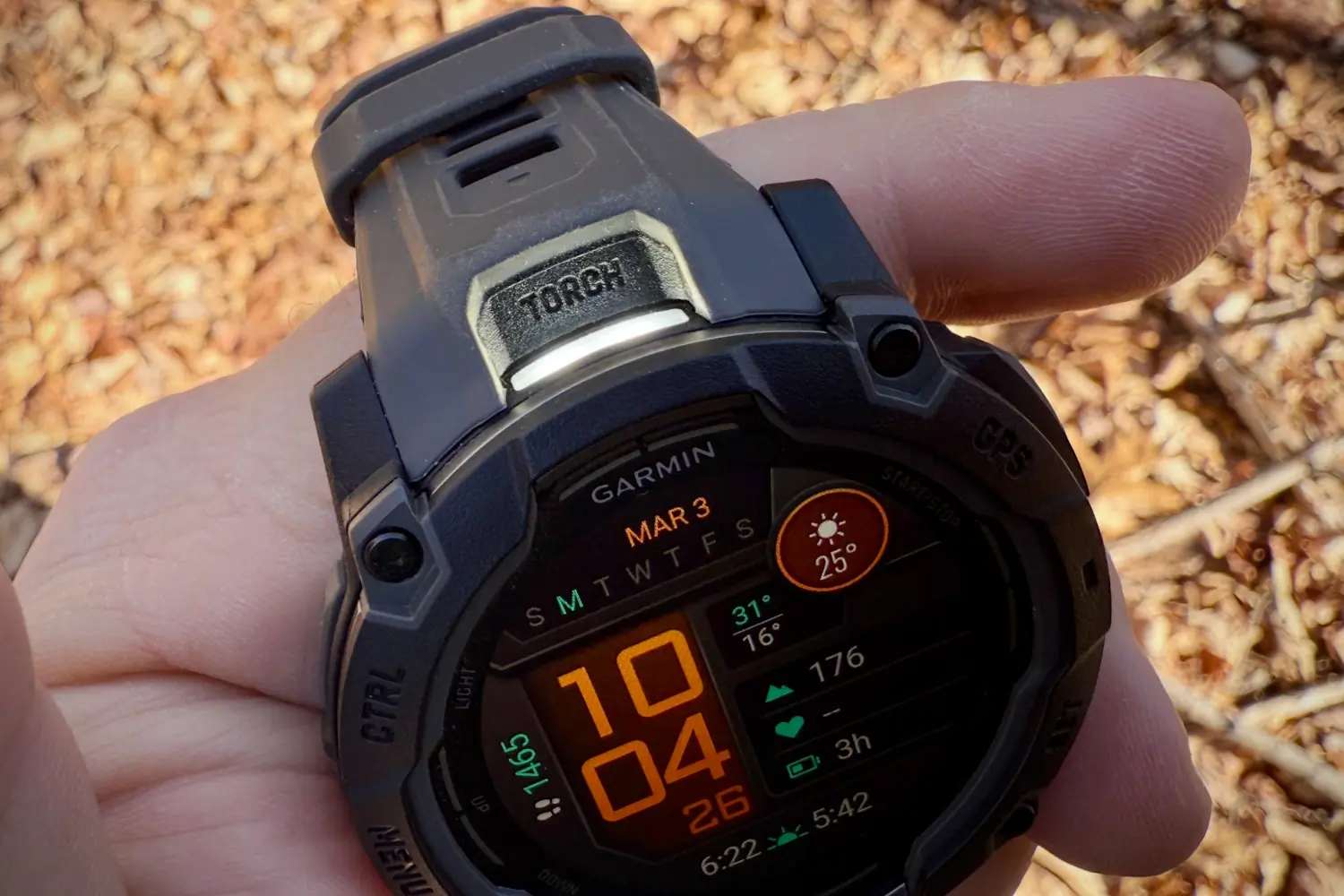 A close-up of a Garmin Instinct 3 smartwatch being held in a person's hand