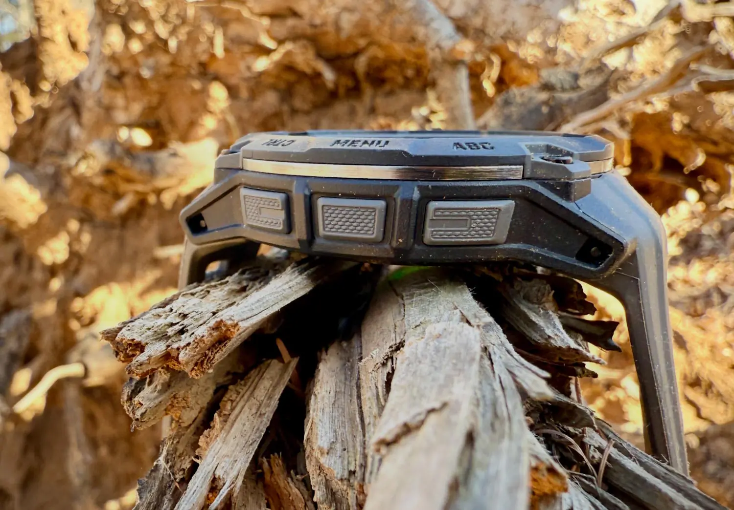 A close-up side view of a Garmin watch resting on a piece of wood