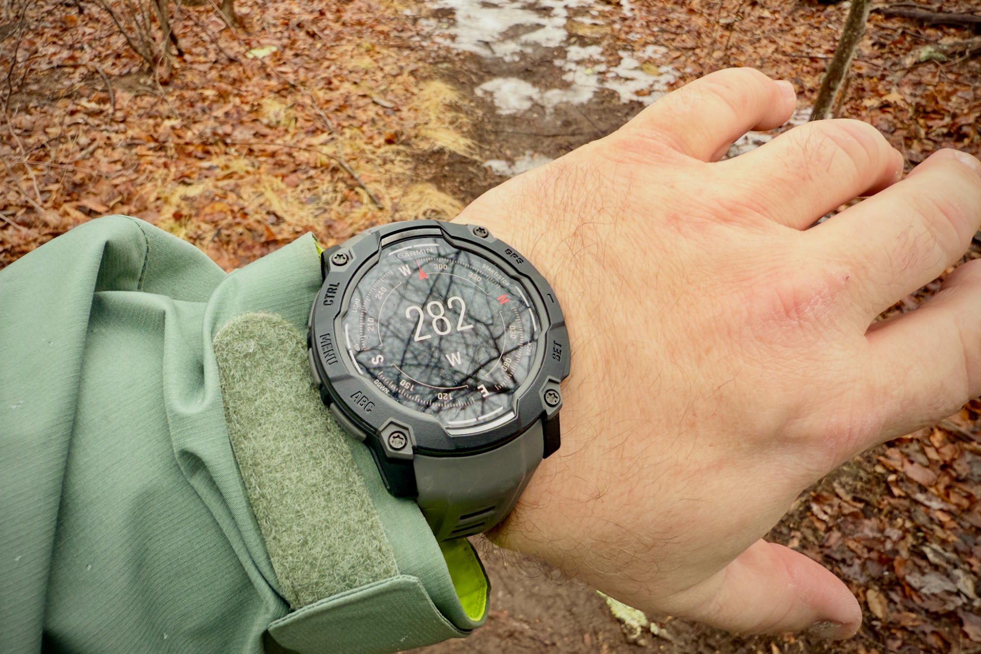 A Garmin Instinct 3 Solar watch displaying a compass heading of 282° (west) on a person's wrist