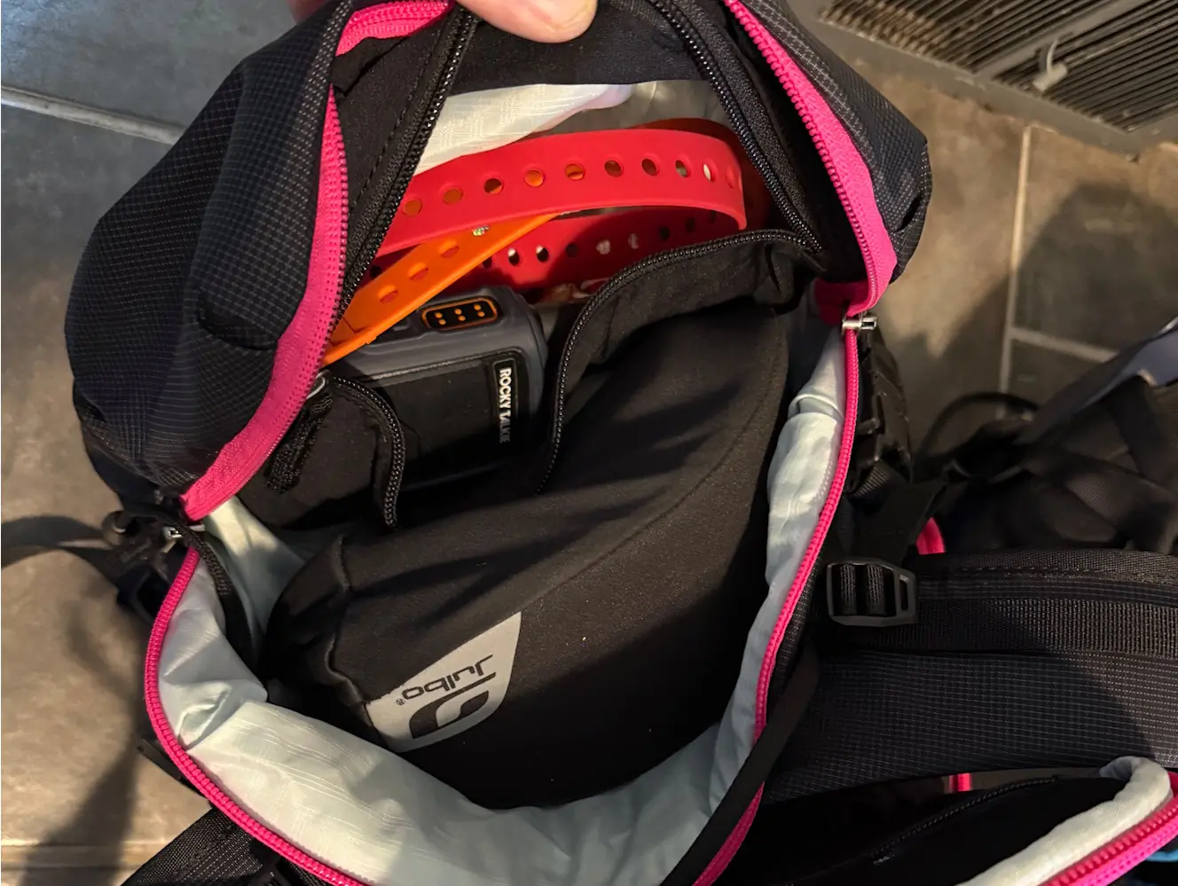 Close-up of the Pingora Vivid 27L backpack’s avalanche tool pocket, showing a beacon, probe, and shovel inside.