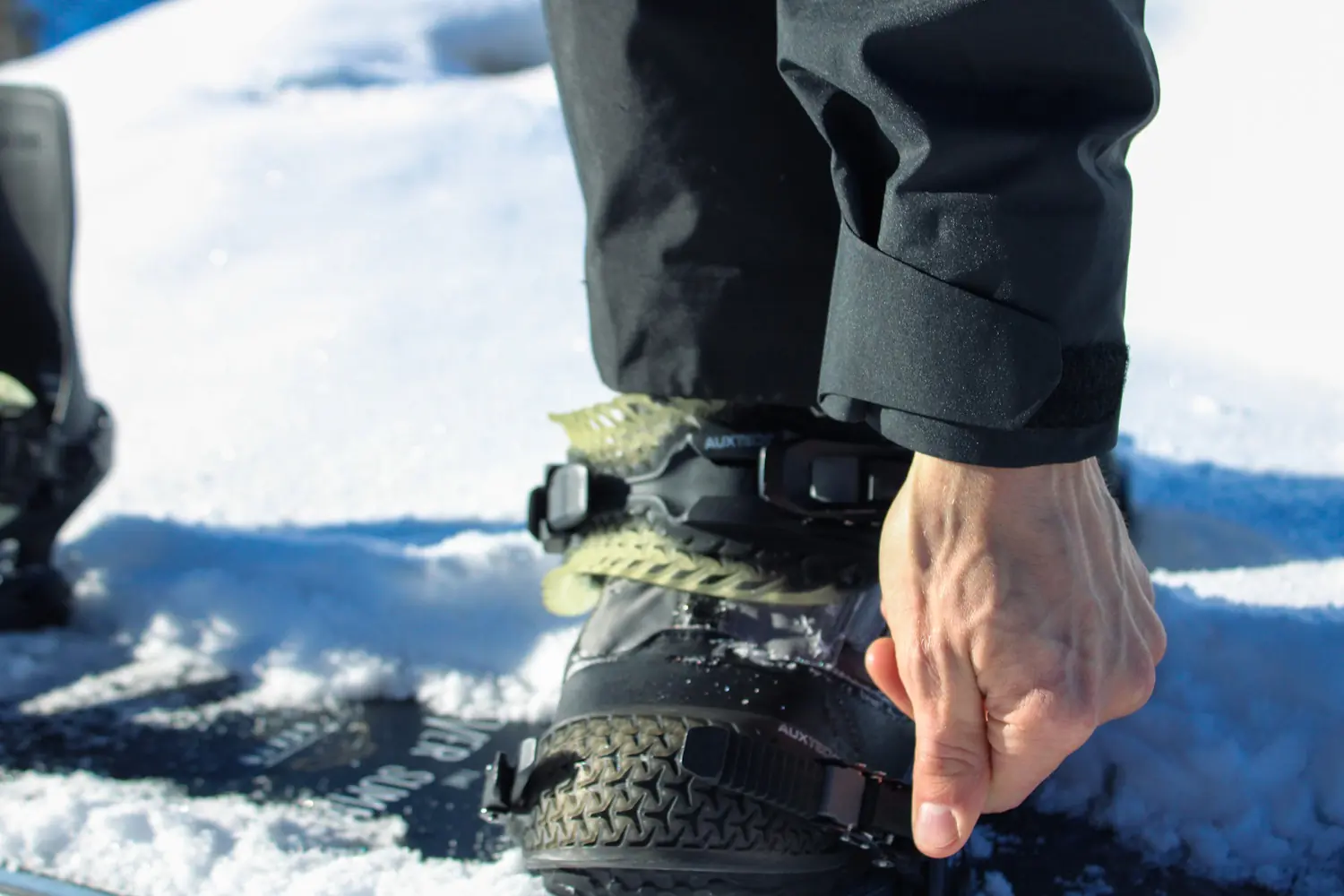 A close-up of a person fastening the straps on their Rome katana pro snowboard bindings 
