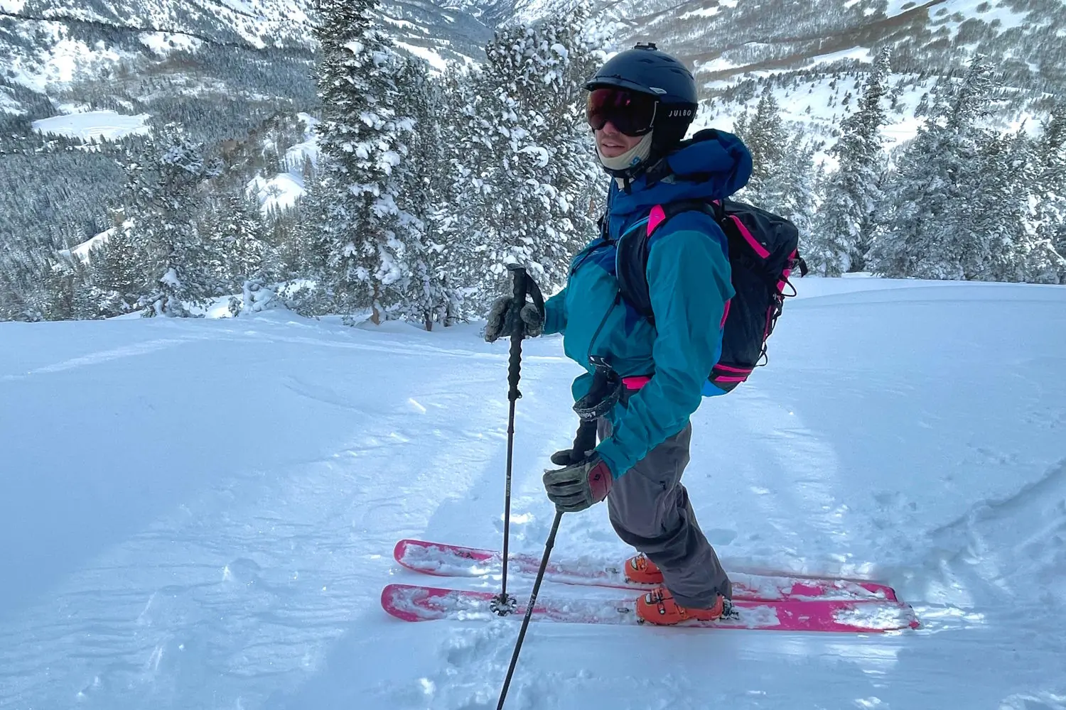 Skier in blue jacket with a Pingora Vivid 27L backpack on a snowy slope