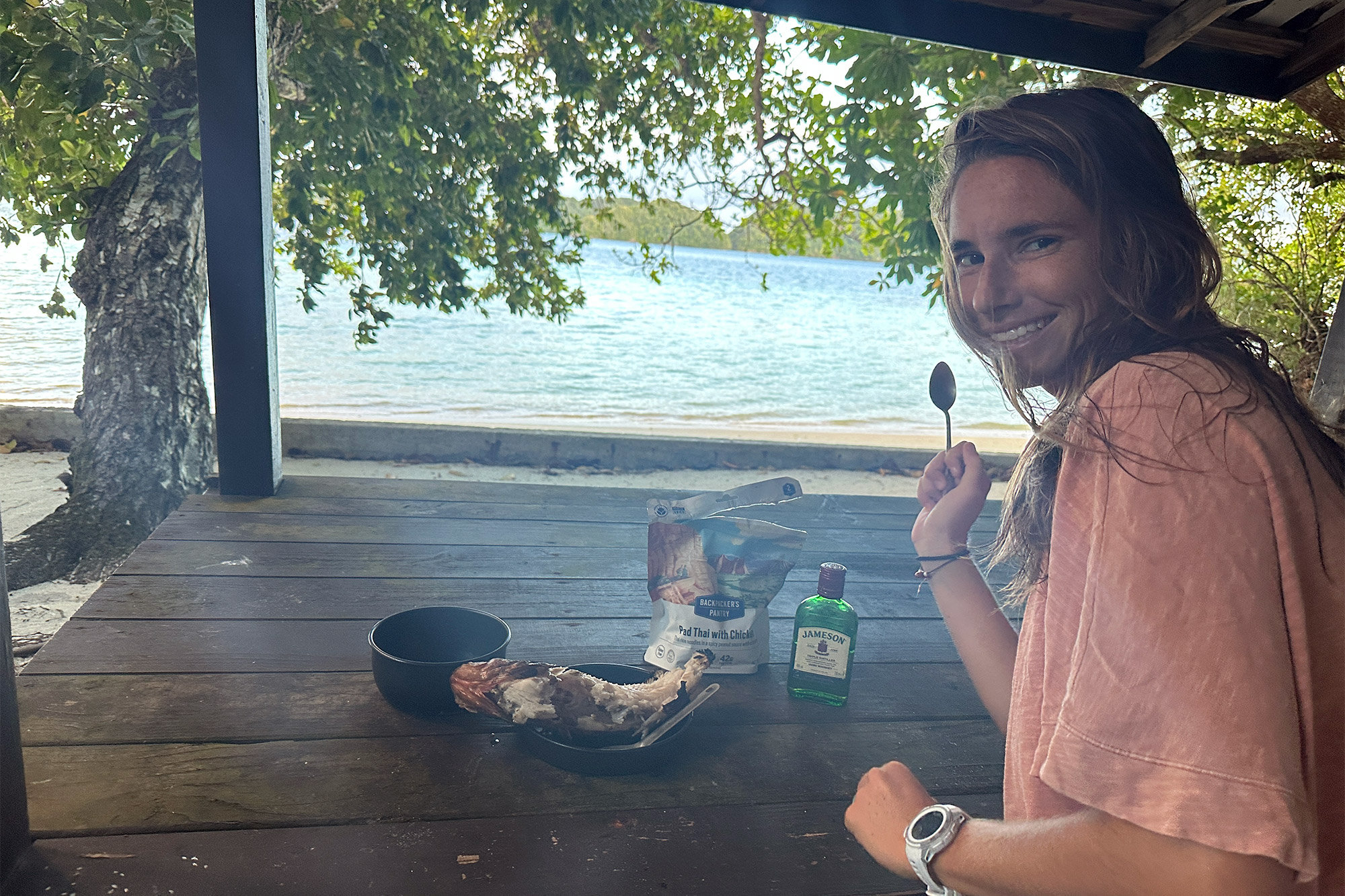 person enjoying a meal with a Trangia stove by the beach