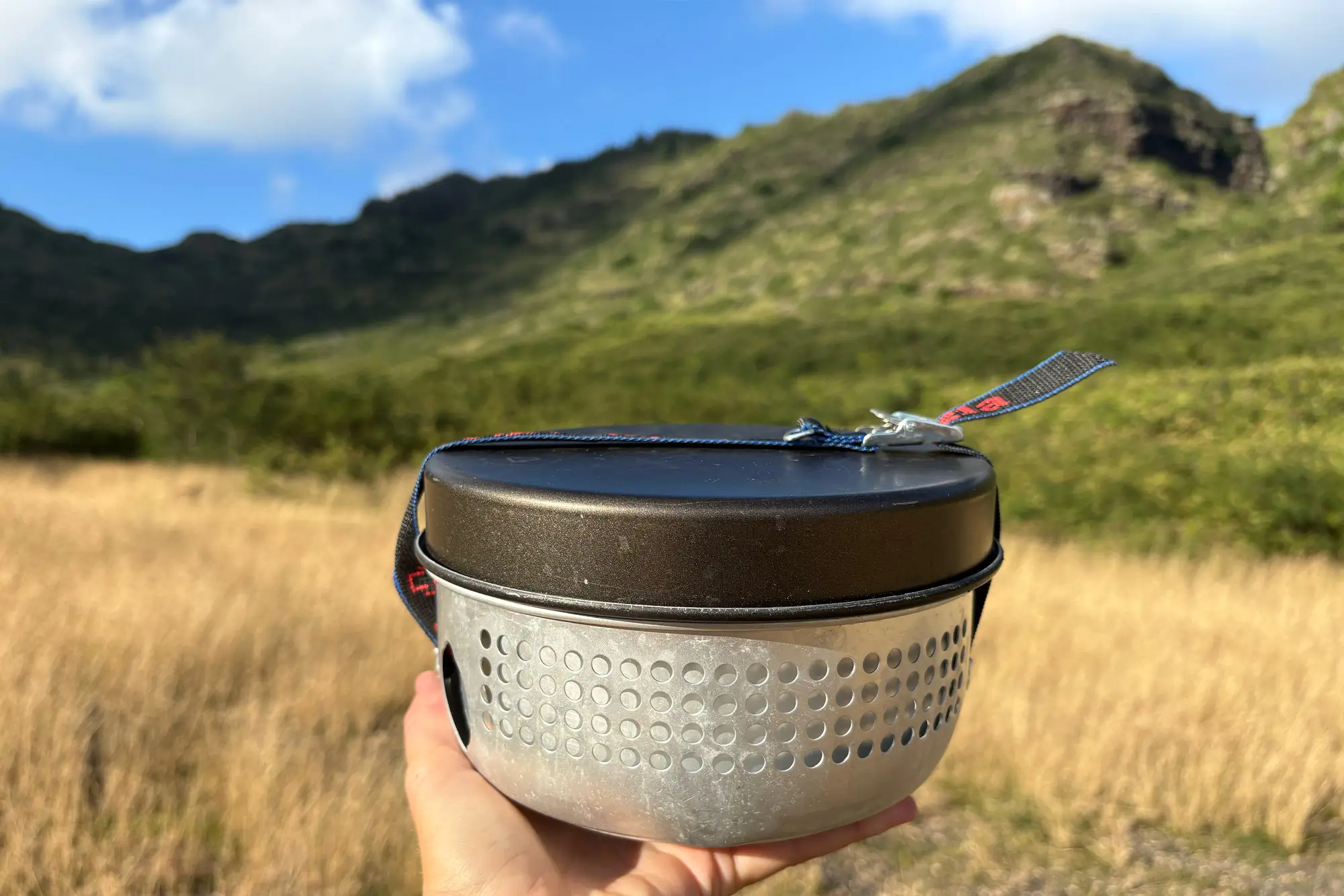 Trangia 27-5 Stove held in hand with a mountain backdrop
