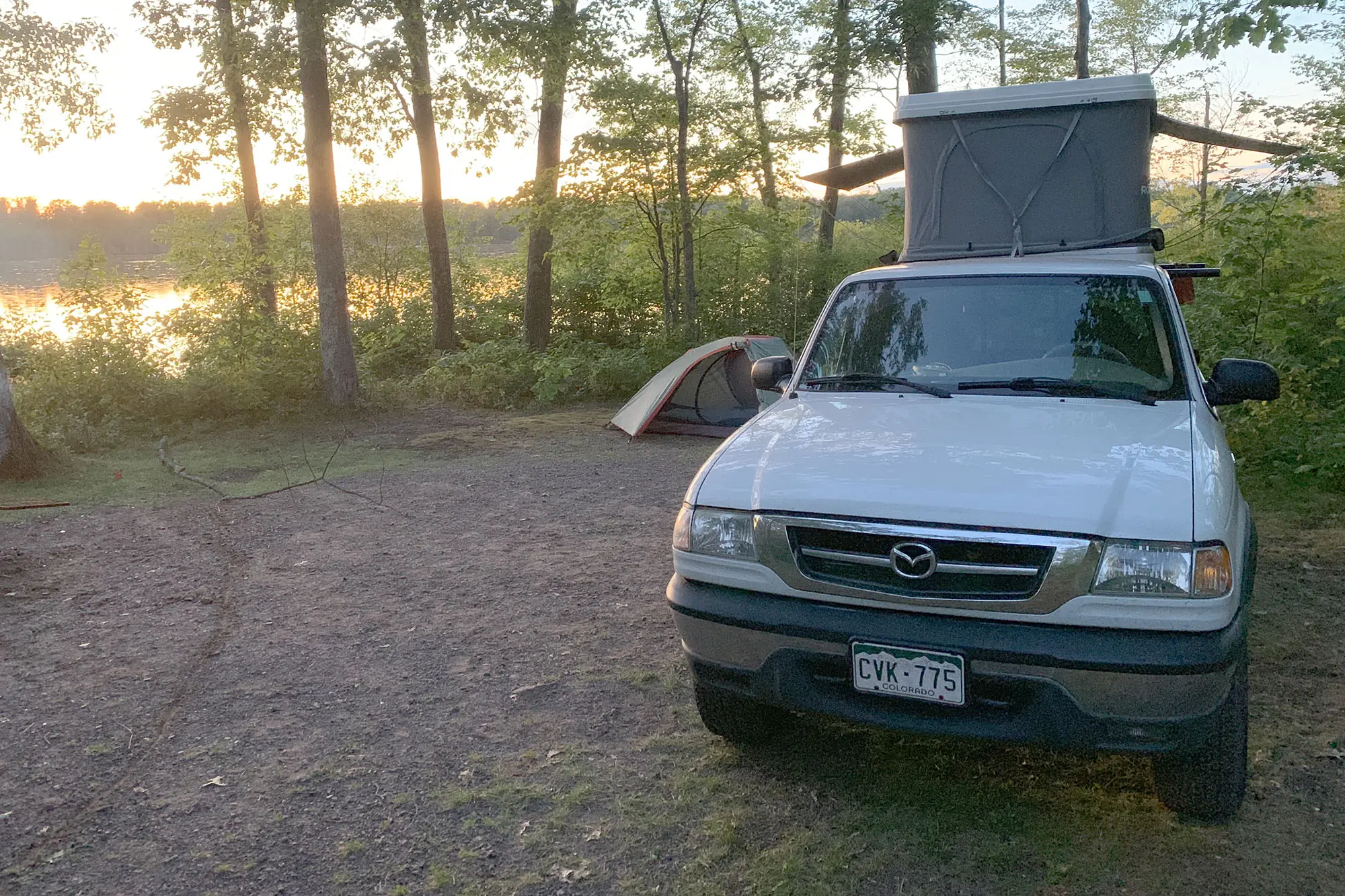 truck with roof top tent parked by lake