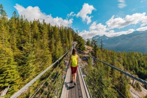 Woman,Hiking,In,Mountains,Crossing,Foot,Suspension,Bridge,With,Amazing