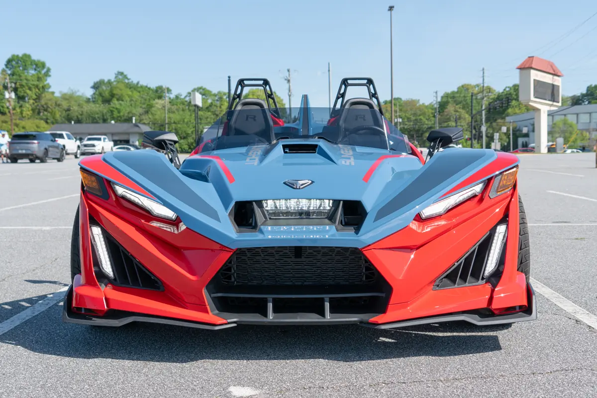 Polaris Slingshot R front view with sharp red and blue styling in a parking lot