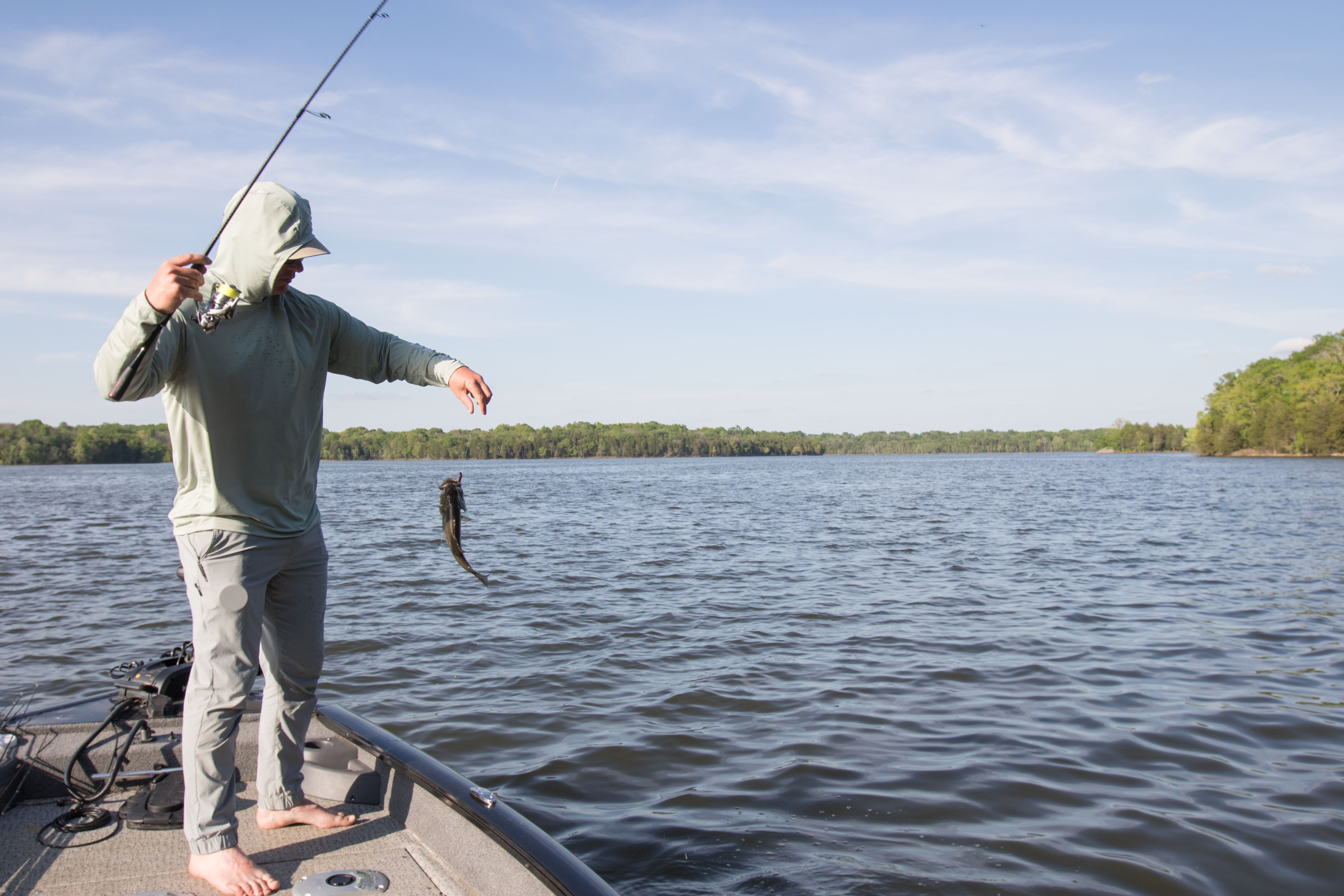 A bass angler lifting a fish out of the water.