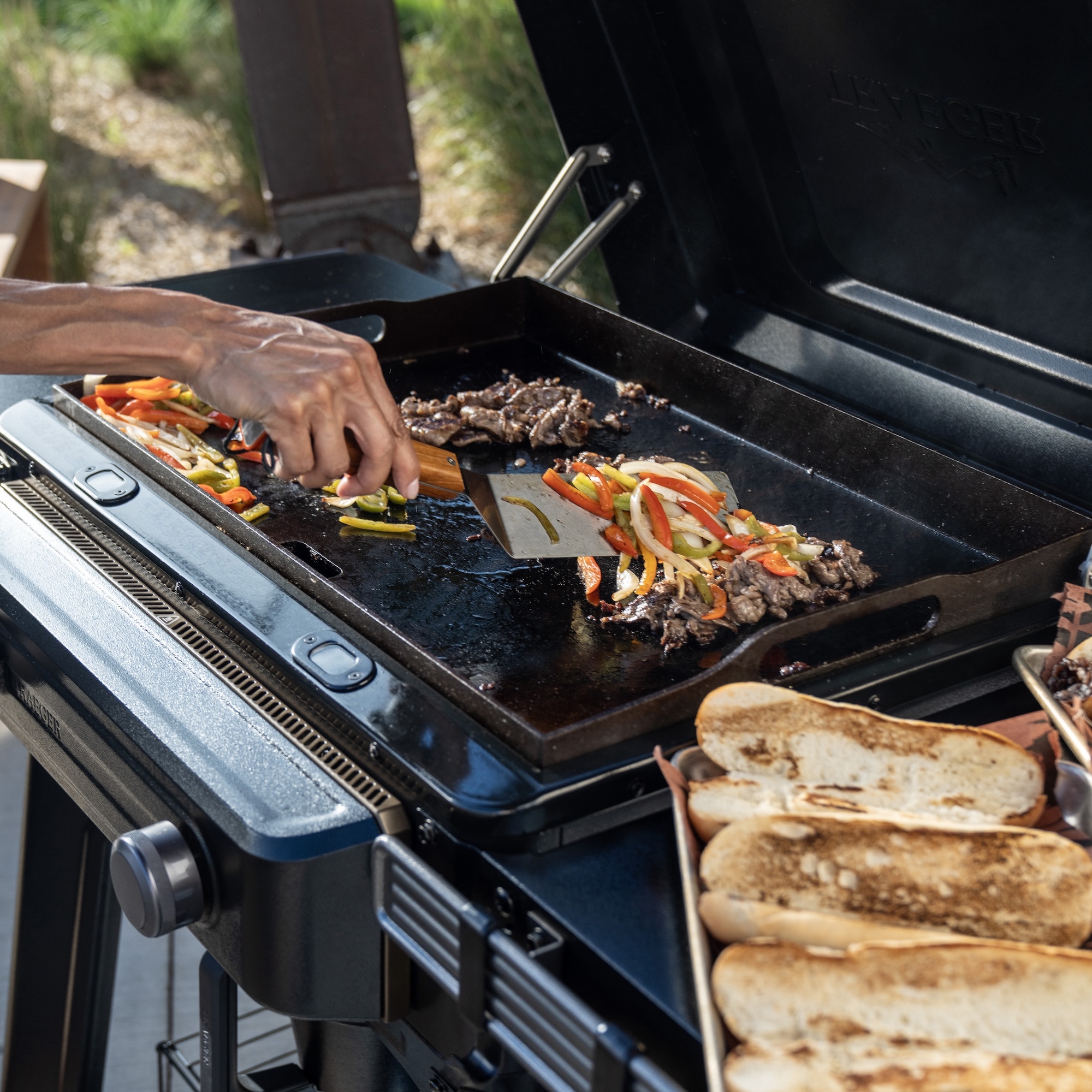grilling veggies, bread, and meet on a flat top grill