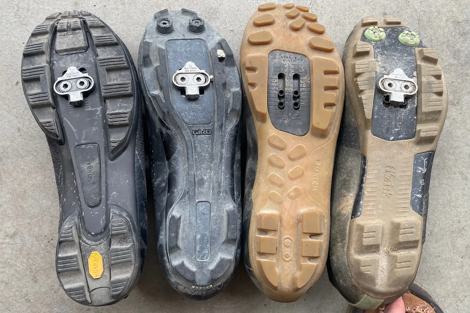 The soles of four different gravel bike shoes for somparison