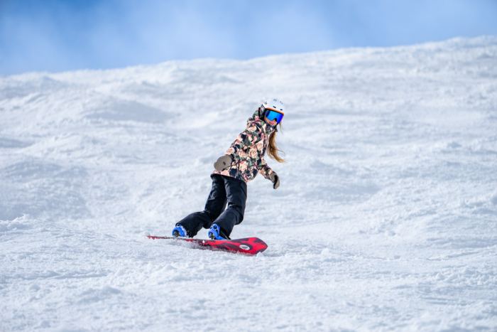 snowboard making toe side carve through choppy slope