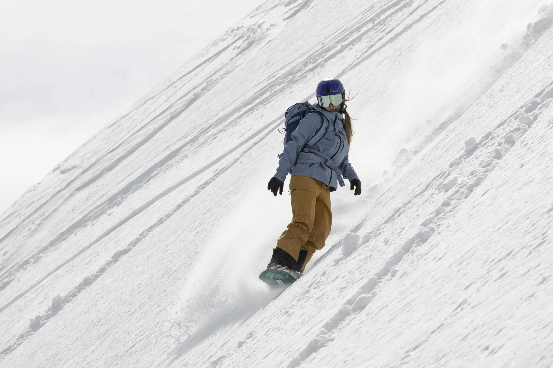 Snowboarder on steep slope in Patagonia PowSlayer shell