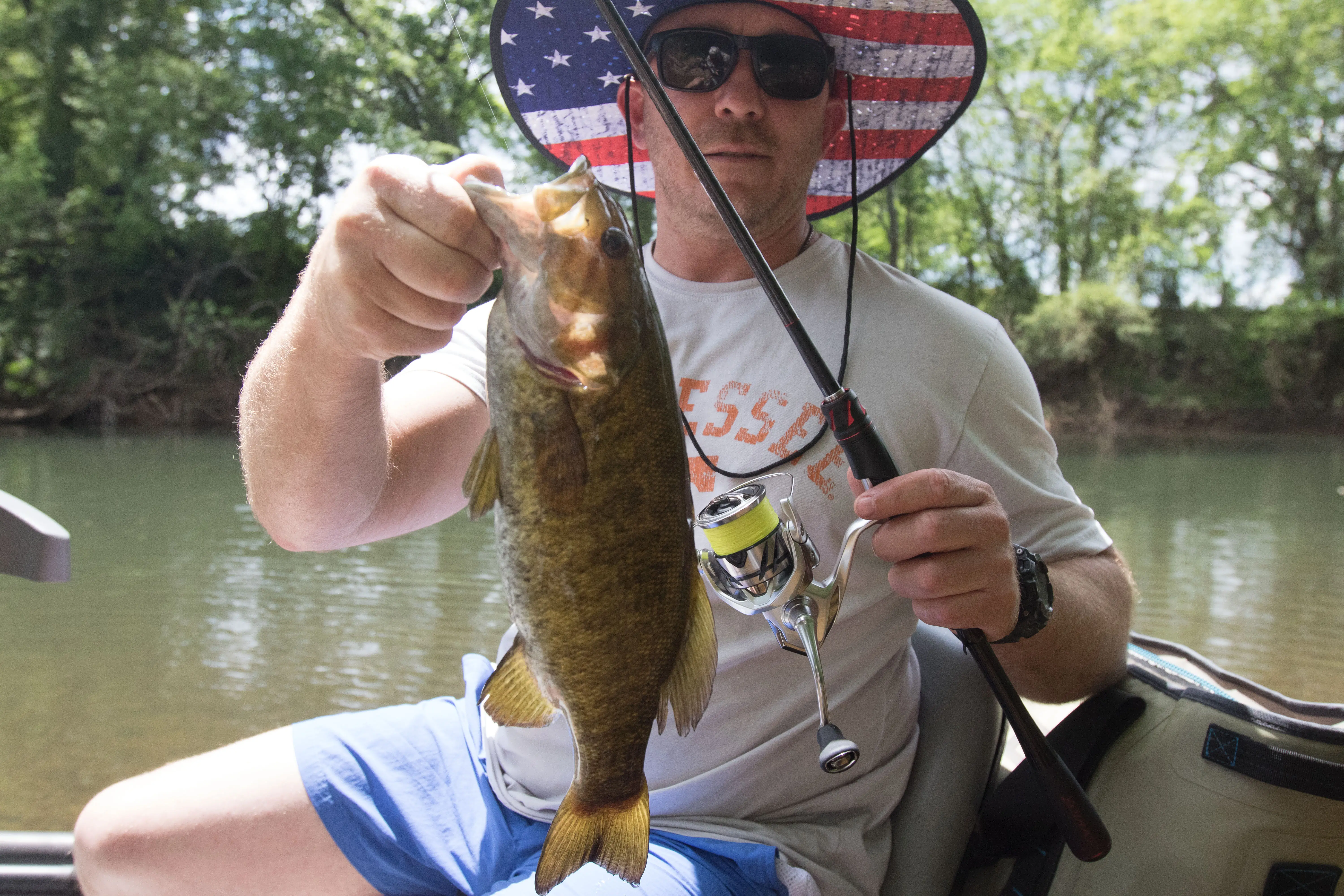 A bass angler holds a fish up that he caught from a small creek.